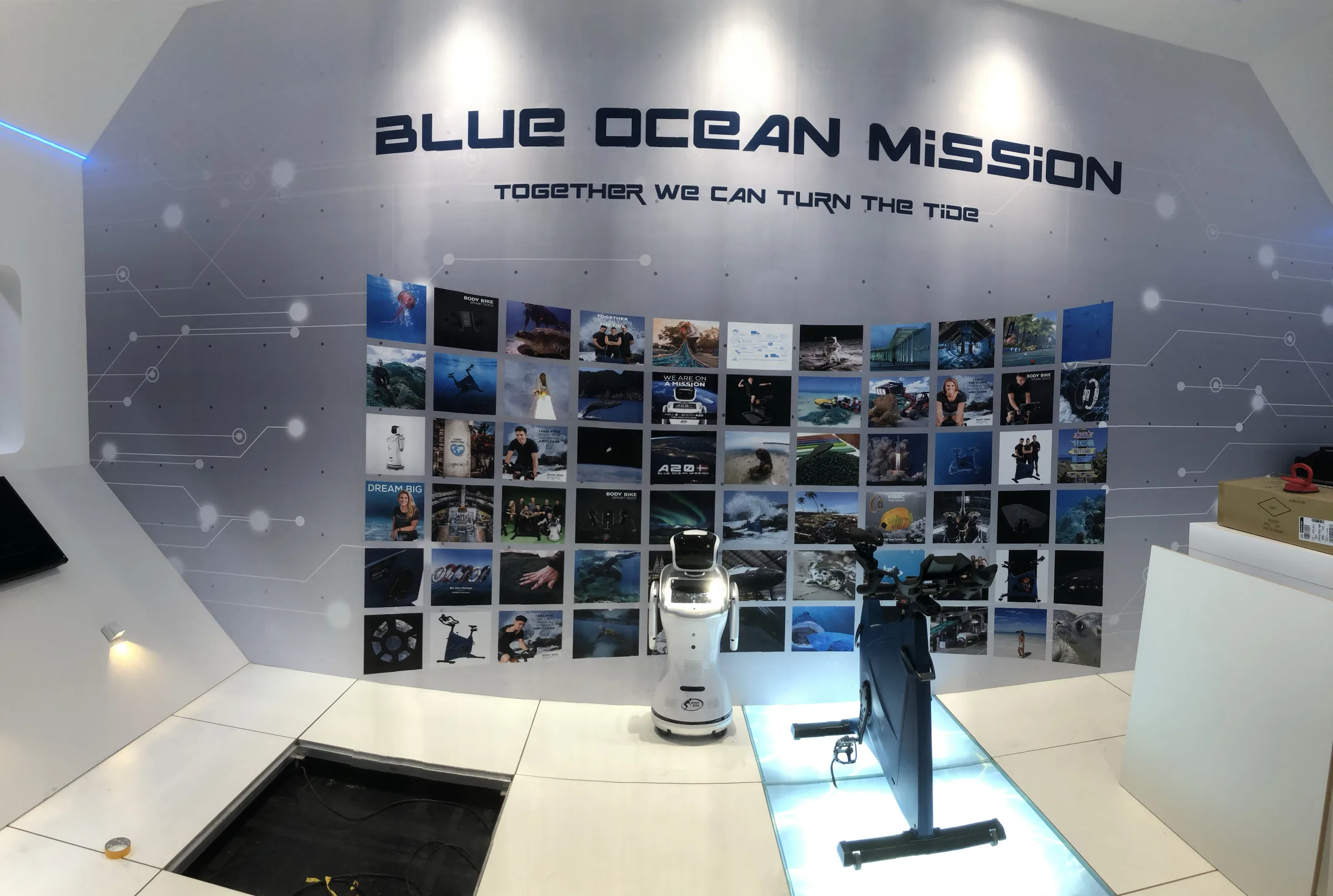 De Blue Ocean Mission in de stand: een wand vol beelden over de oceaan onder de tekst Together we can turn the tide, met de OceanIX-fiets ervoor.