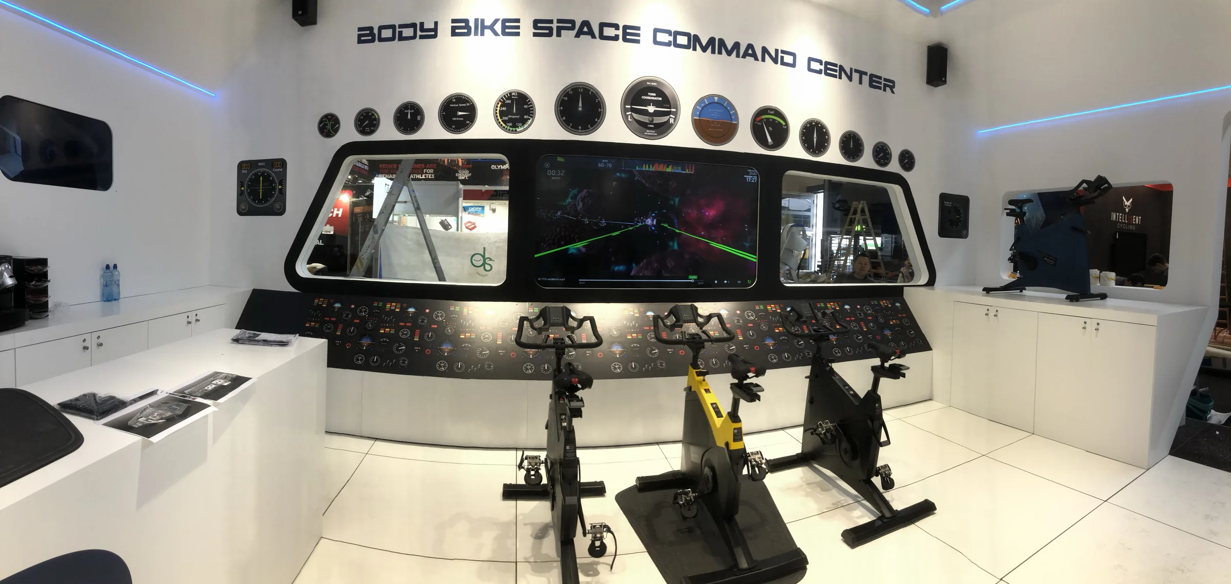 Het BODY BIKE Space Command Center in de stand: een cockpit met schermen en meters, met drie BODY BIKE SMART-fietsen ervoor.