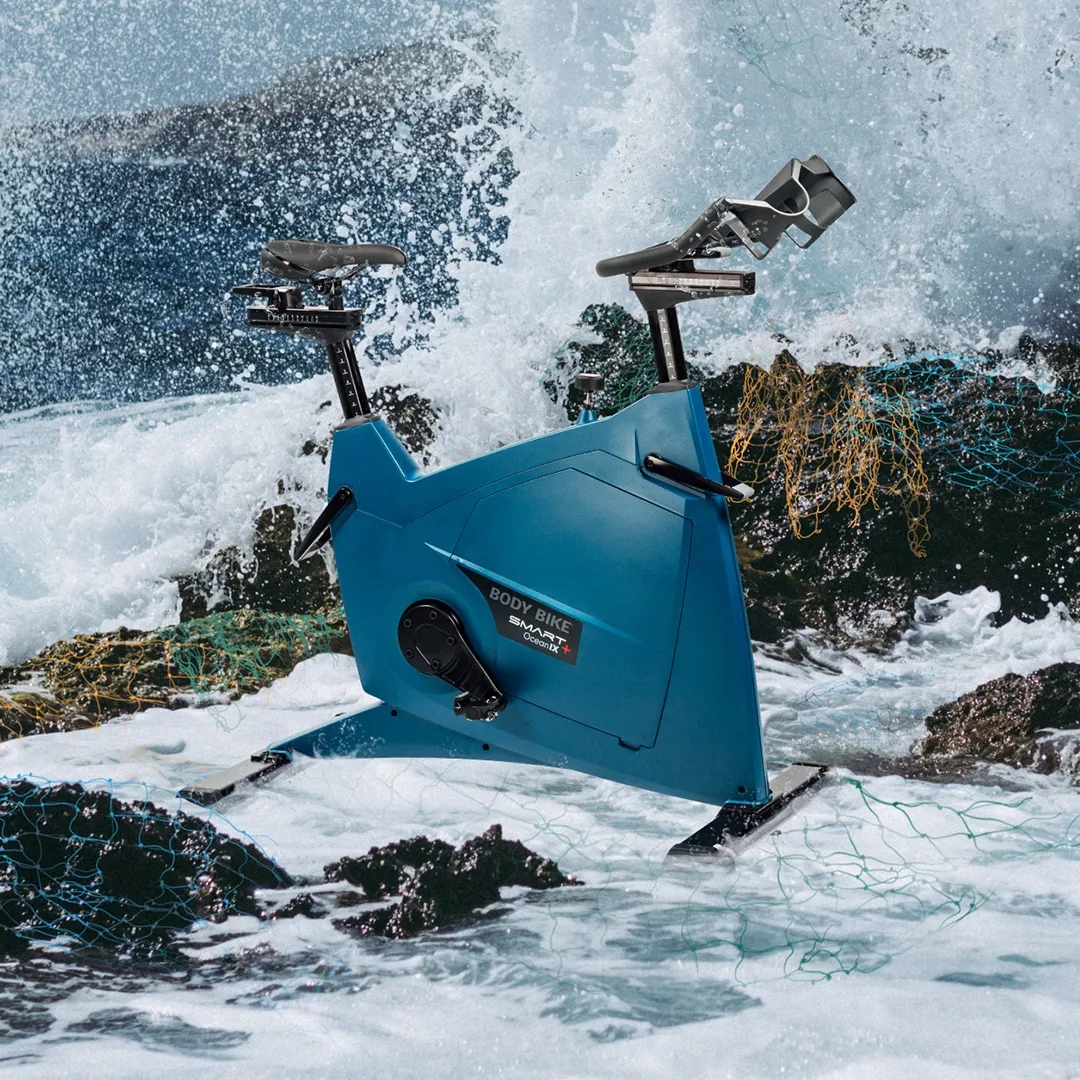 De blauwe OceanIX-fiets op de rotsen in de branding.